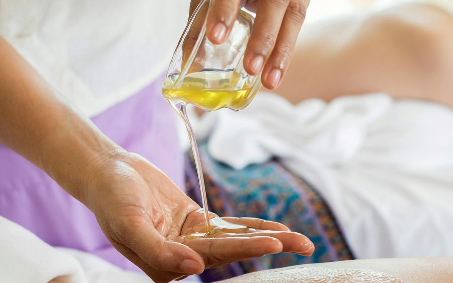 Aceite tibio servido en la mano antes de comenzar el masaje